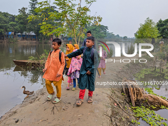 Children go to school in the early morning in a rural area in Feni, Bangladesh, on October 16, 2024. Many fish enclosures and ponds are wash...