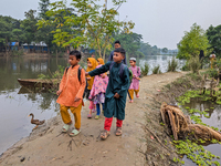 Children go to school in the early morning in a rural area in Feni, Bangladesh, on October 16, 2024. Many fish enclosures and ponds are wash...