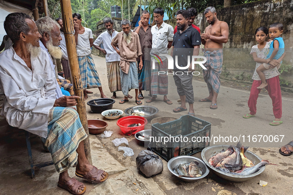 Fishermen sell fish in the early morning in a rural area in Feni, Bangladesh, on October 16, 2024. Many fish enclosures and ponds are washed...