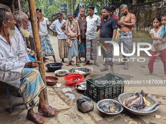 Fishermen sell fish in the early morning in a rural area in Feni, Bangladesh, on October 16, 2024. Many fish enclosures and ponds are washed...