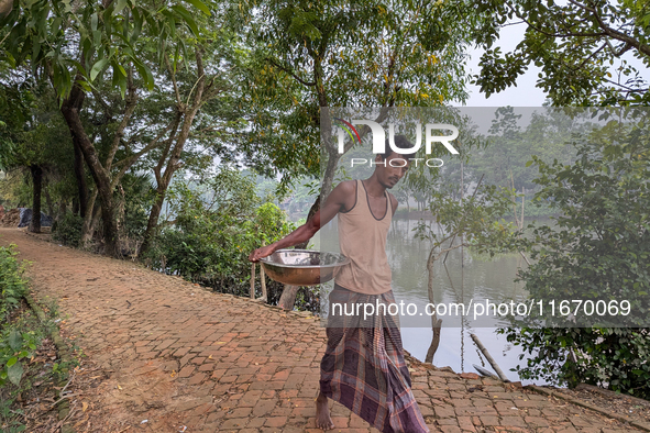 A fisherman sells fish in a rural market in a rural area in Feni, Bangladesh, on October 16, 2024. Many fish enclosures and ponds are washed...