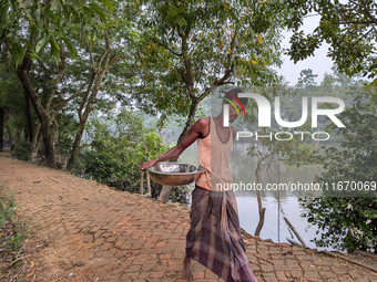 A fisherman sells fish in a rural market in a rural area in Feni, Bangladesh, on October 16, 2024. Many fish enclosures and ponds are washed...