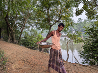 A fisherman sells fish in a rural market in a rural area in Feni, Bangladesh, on October 16, 2024. Many fish enclosures and ponds are washed...