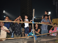 People stand and watch a street-side barricade in a procession with Durga idols before the immersion of the statue of Goddess Durga into the...