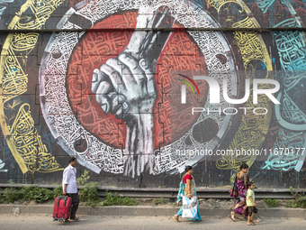 People walk past Arabic calligraphy in Dhaka, Bangladesh, on October 14, 2024. (