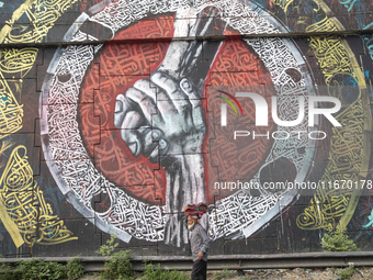 People walk past Arabic calligraphy in Dhaka, Bangladesh, on October 14, 2024. (