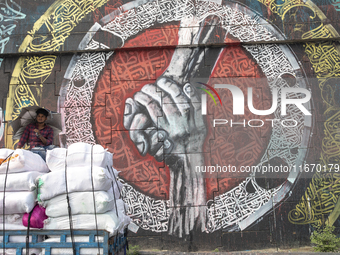 People walk past Arabic calligraphy in Dhaka, Bangladesh, on October 14, 2024. (