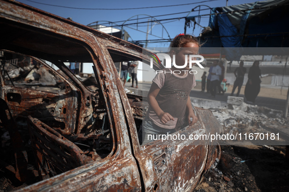 A displaced Palestinian girl looks out from a destroyed car due to an Israeli airstrike on the tents of the displaced inside the Al-Aqsa Mar...