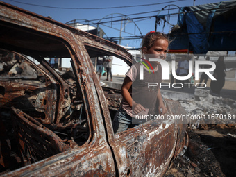 A displaced Palestinian girl looks out from a destroyed car due to an Israeli airstrike on the tents of the displaced inside the Al-Aqsa Mar...