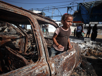 A displaced Palestinian girl looks out from a destroyed car due to an Israeli airstrike on the tents of the displaced inside the Al-Aqsa Mar...