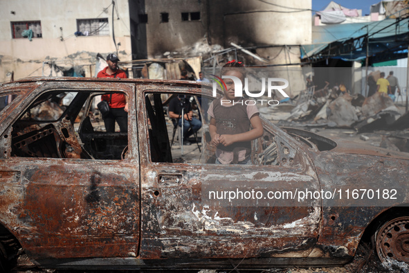 A displaced Palestinian girl looks out from a destroyed car due to an Israeli airstrike on the tents of the displaced inside the Al-Aqsa Mar...