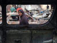 A displaced Palestinian girl looks out from a destroyed car due to an Israeli airstrike on the tents of the displaced inside the Al-Aqsa Mar...