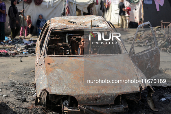 A displaced Palestinian boy looks out from a destroyed car due to an Israeli airstrike on the tents of the displaced inside the Al-Aqsa Mart...