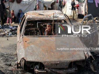 A displaced Palestinian boy looks out from a destroyed car due to an Israeli airstrike on the tents of the displaced inside the Al-Aqsa Mart...