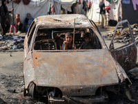 A displaced Palestinian boy looks out from a destroyed car due to an Israeli airstrike on the tents of the displaced inside the Al-Aqsa Mart...