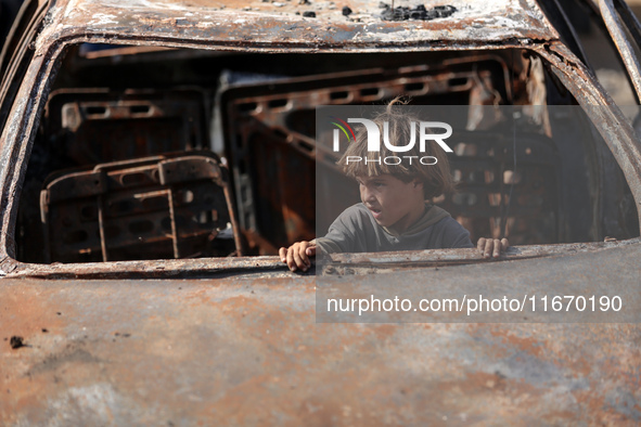 A displaced Palestinian boy looks out from a destroyed car due to an Israeli airstrike on the tents of the displaced inside the Al-Aqsa Mart...