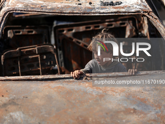 A displaced Palestinian boy looks out from a destroyed car due to an Israeli airstrike on the tents of the displaced inside the Al-Aqsa Mart...