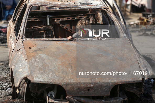 A displaced Palestinian boy looks out from a destroyed car due to an Israeli airstrike on the tents of the displaced inside the Al-Aqsa Mart...