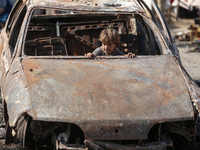 A displaced Palestinian boy looks out from a destroyed car due to an Israeli airstrike on the tents of the displaced inside the Al-Aqsa Mart...