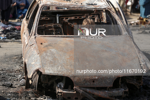 A displaced Palestinian boy looks out from a destroyed car due to an Israeli airstrike on the tents of the displaced inside the Al-Aqsa Mart...