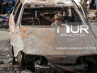 A displaced Palestinian boy looks out from a destroyed car due to an Israeli airstrike on the tents of the displaced inside the Al-Aqsa Mart...