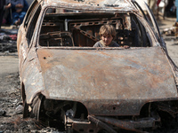 A displaced Palestinian boy looks out from a destroyed car due to an Israeli airstrike on the tents of the displaced inside the Al-Aqsa Mart...