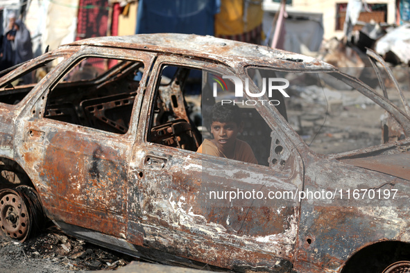 A displaced Palestinian boy looks out from a destroyed car due to an Israeli airstrike on the tents of the displaced inside the Al-Aqsa Mart...