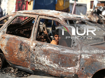 A displaced Palestinian boy looks out from a destroyed car due to an Israeli airstrike on the tents of the displaced inside the Al-Aqsa Mart...