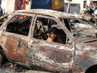 A displaced Palestinian boy looks out from a destroyed car due to an Israeli airstrike on the tents of the displaced inside the Al-Aqsa Mart...