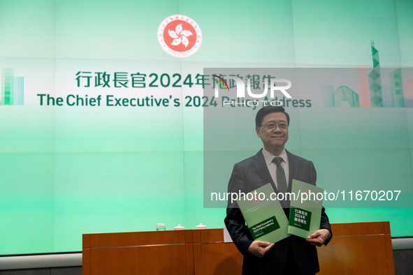 Hong Kong Chief Executive John Lee holds up booklets of his 2024 policy address while posing for a photo before a press conference in Hong K...