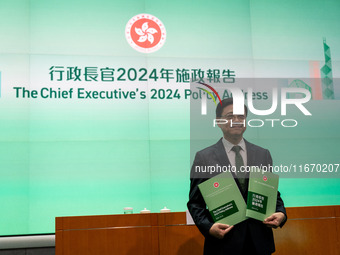 Hong Kong Chief Executive John Lee holds up booklets of his 2024 policy address while posing for a photo before a press conference in Hong K...