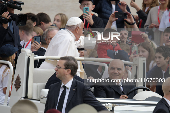 Pope Francis caresses a baby from his popemobile as he arrives for the weekly general audience at Saint Peter's Square in The Vatican on Oct...