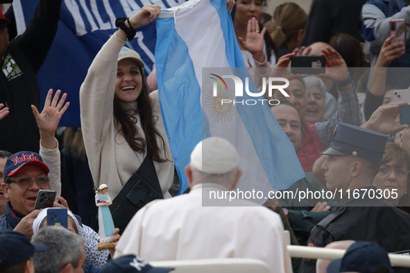 A pilgrim waves the Argentine flag when Pope Francis arrives in St. Peter's Square in Vatican City, on October 16, 2024, for the weekly gene...