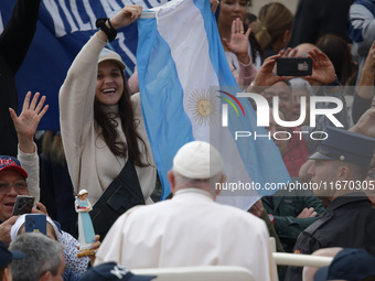 A pilgrim waves the Argentine flag when Pope Francis arrives in St. Peter's Square in Vatican City, on October 16, 2024, for the weekly gene...