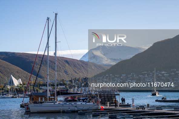 A view of the harbor of Tromso with the Tromsdalstinden mountain in background and the Arctic Cathedral on the left, in Tromso, Norway on Se...