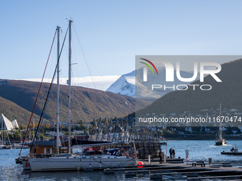 A view of the harbor of Tromso with the Tromsdalstinden mountain in background and the Arctic Cathedral on the left, in Tromso, Norway on Se...