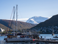 A view of the harbor of Tromso with the Tromsdalstinden mountain in background and the Arctic Cathedral on the left, in Tromso, Norway on Se...