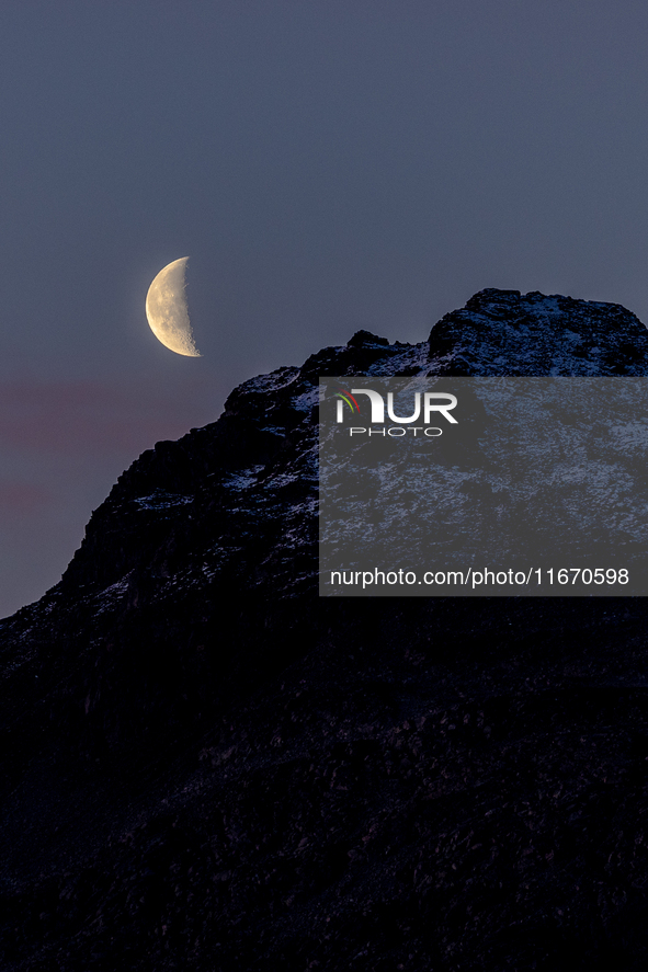 A view of waning crescent moon over the snowy mountains of Tromso, Norway on September 25, 2024.  