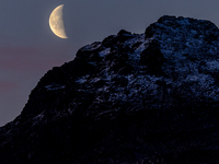 A view of waning crescent moon over the snowy mountains of Tromso, Norway on September 25, 2024.  (