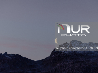 A view of waning crescent moon over the snowy mountains of Tromso, Norway on September 25, 2024.  (