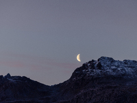 A view of waning crescent moon over the snowy mountains of Tromso, Norway on September 25, 2024.  (