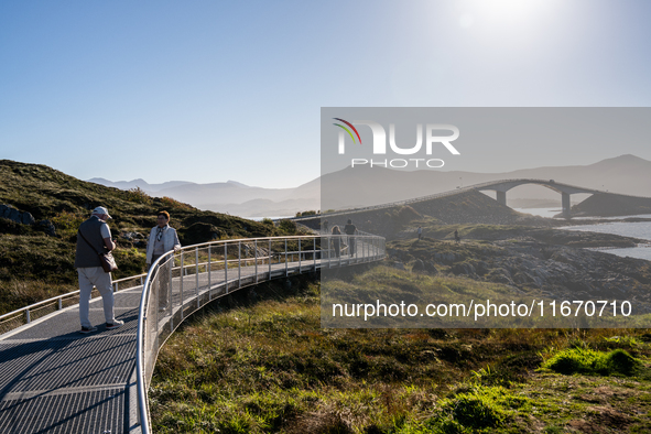 Tourists walk along a scenic pathway near a bridge on the Atlantic Ocean Road in Norway, on September 18, 2024. The Atlantic Road in Norway...