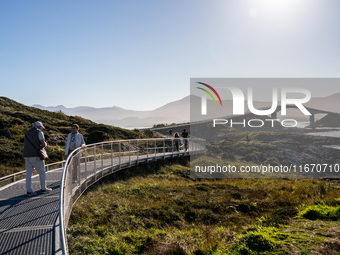 Tourists walk along a scenic pathway near a bridge on the Atlantic Ocean Road in Norway, on September 18, 2024. The Atlantic Road in Norway...