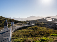 Tourists walk along a scenic pathway near a bridge on the Atlantic Ocean Road in Norway, on September 18, 2024. The Atlantic Road in Norway...