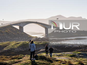 Tourists walk along a scenic pathway near a bridge on the Atlantic Ocean Road in Norway, on September 18, 2024. The Atlantic Road in Norway...