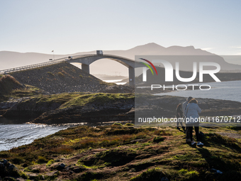 Tourists walk along a scenic pathway near a bridge on the Atlantic Ocean Road in Norway, on September 18, 2024. The Atlantic Road in Norway...