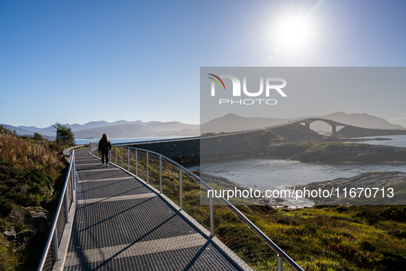 Tourists walk along a scenic pathway near a bridge on the Atlantic Ocean Road in Norway, on September 18, 2024. The Atlantic Road in Norway...