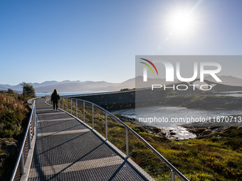 Tourists walk along a scenic pathway near a bridge on the Atlantic Ocean Road in Norway, on September 18, 2024. The Atlantic Road in Norway...