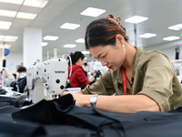 Workers rush to fulfill export orders at the clothing production line of Shaanxi Yanzhong Garment Co., Ltd. in Weinan, China, on October 15,...