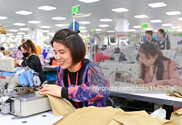 Workers rush to fulfill export orders at the clothing production line of Shaanxi Yanzhong Garment Co., Ltd. in Weinan, China, on October 15,...